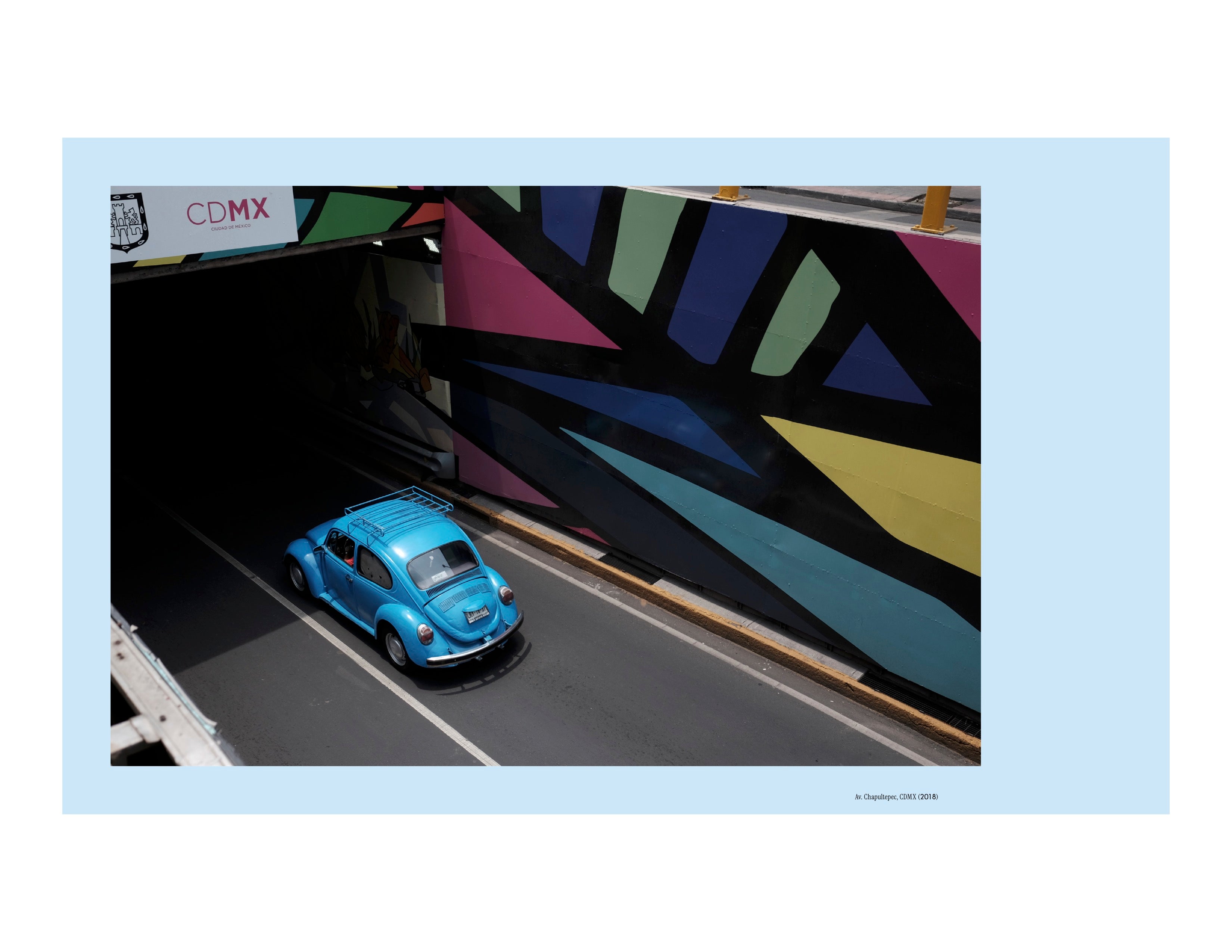 Image of a blue Volkswagen Beetle entering a tunnel with vibrant murals in Mexico City, in a spread from the new book Vochos Unidos by Rodrigo Gaya Villar, published by Carrara Media. A coffee table book of automotive photography showing the Volkswagen Beetle across Mexico, aka "El Vocho." Available now.
