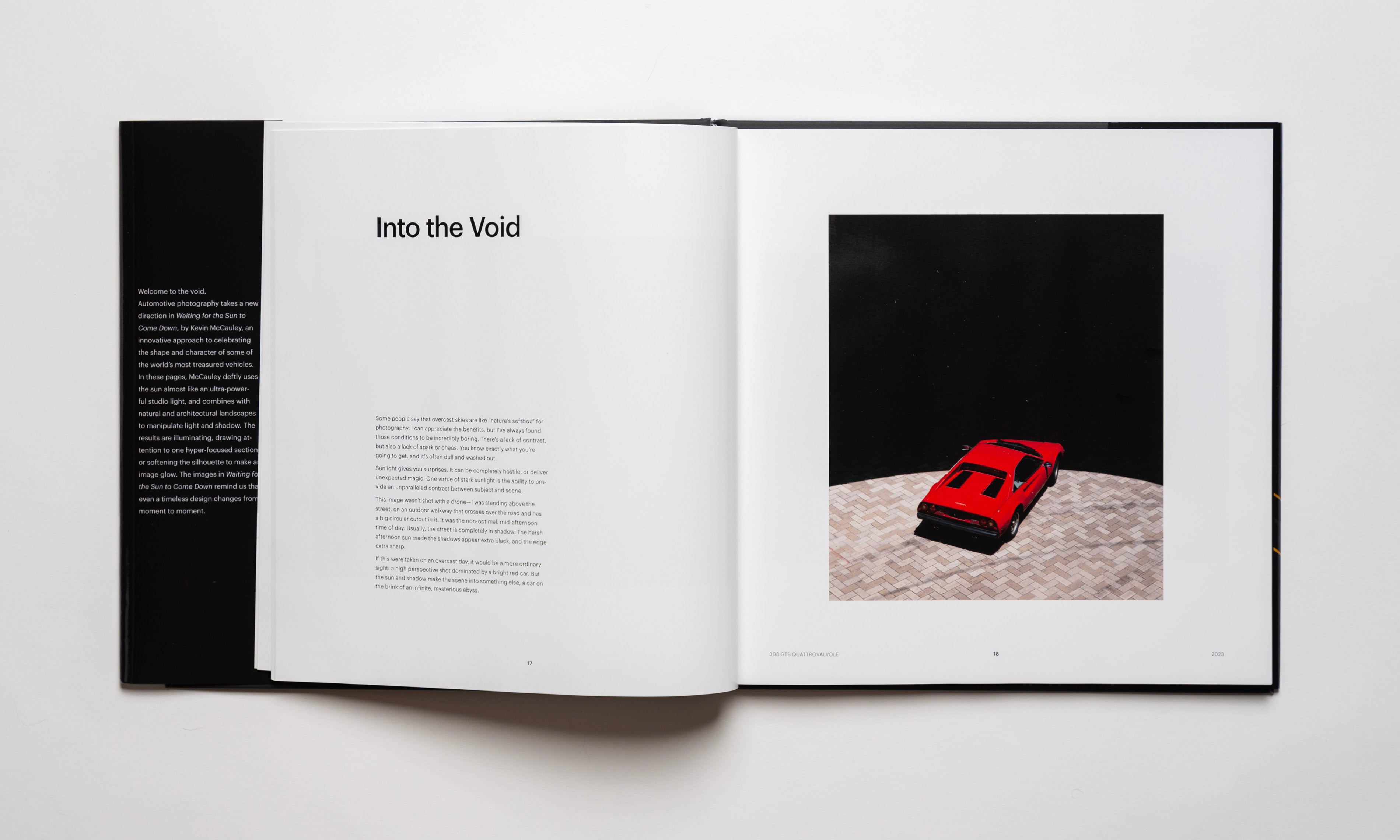 Inside spread of the automotive photography book Waiting For The Sun To Come Down by Kevin McCauley, open to a page entitled "Into The Void" opposite photo of a bright red Ferrari 308 GTB pointing toward an endless black shadow. Published by Carrara Media.