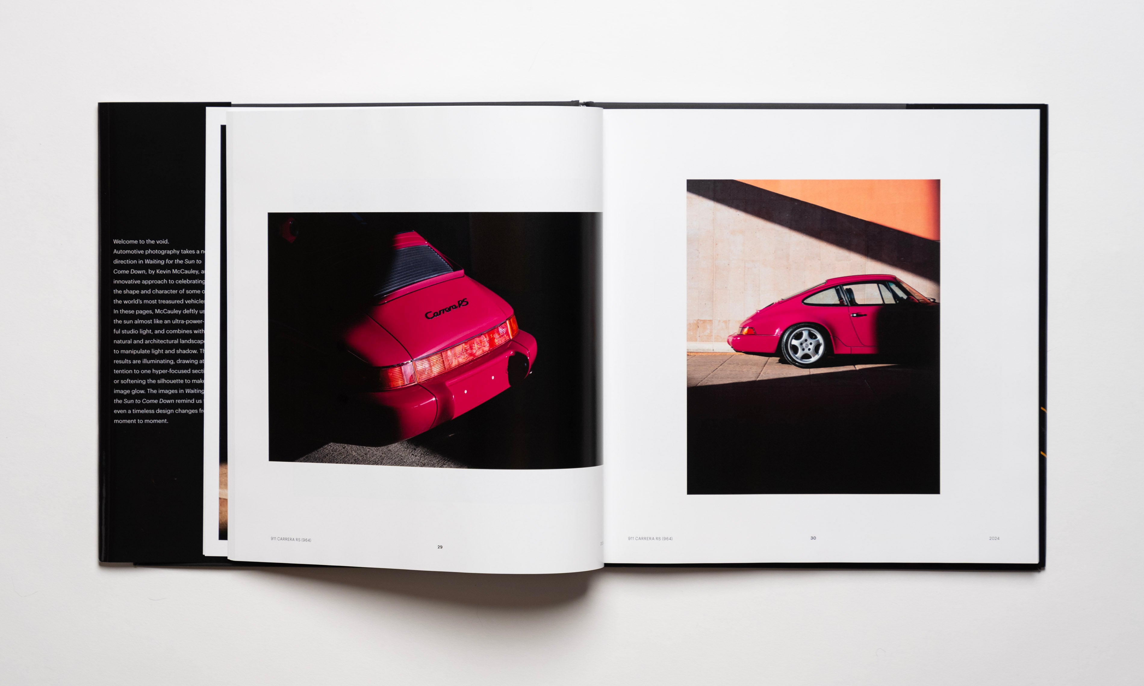 Inside spread of the automotive photography book Waiting For The Sun To Come Down by Kevin McCauley, open to images of a ruby red Porsche 911 Carrera RS with stunning shadows. Published by Carrara Media.